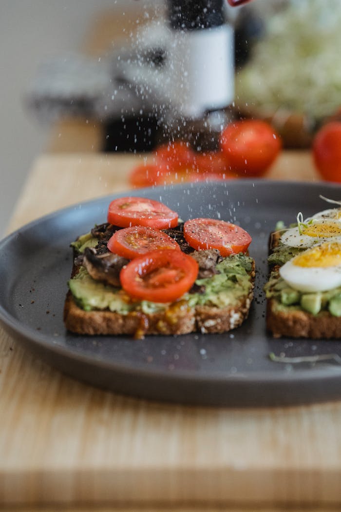 Delicious avocado toast topped with cherry tomatoes and a boiled egg, perfect for breakfast.